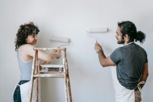 Couple painting walls with white paint