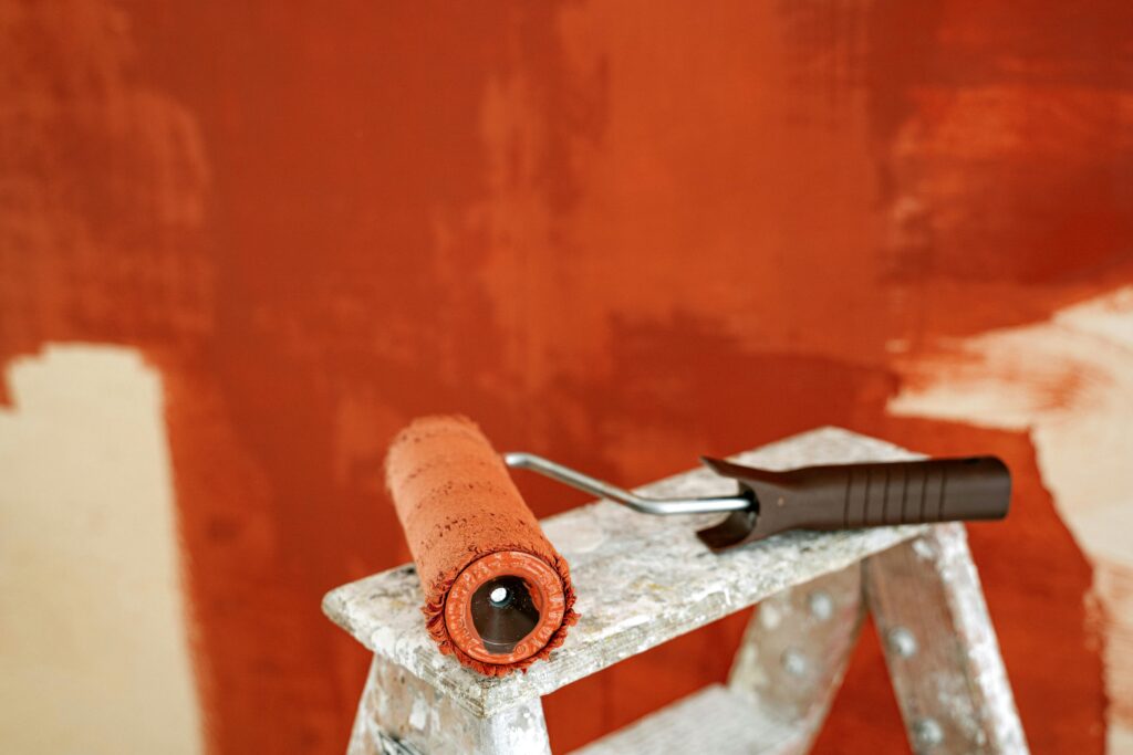 Pint brush with red paint on it on a ladder